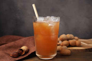 Photo of Freshly made tamarind juice and fresh fruits on wooden table, closeup