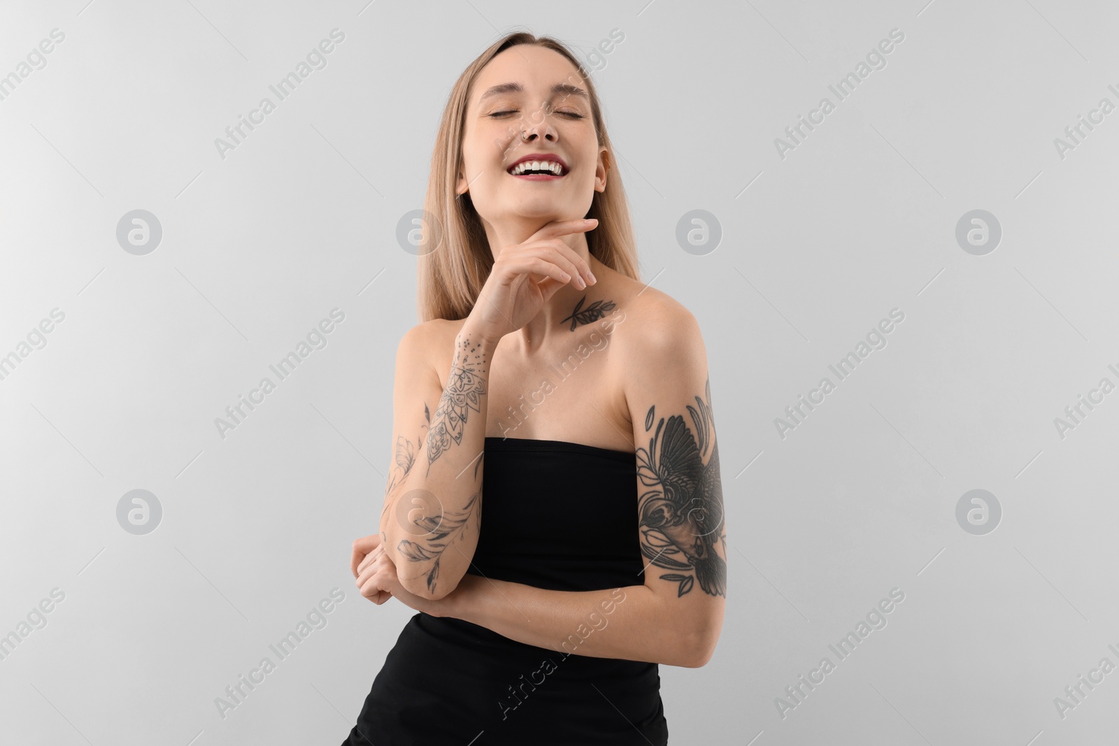 Photo of Portrait of beautiful tattooed woman on light background