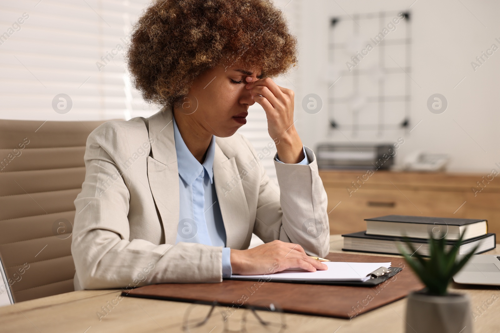 Photo of Woman suffering from headache at workplace in office