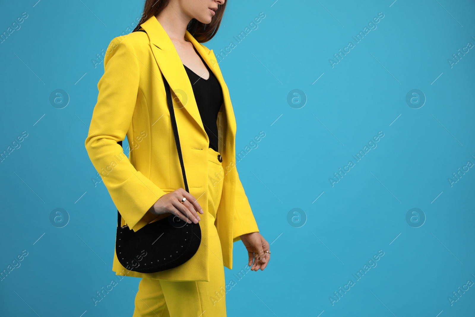 Photo of Fashionable young woman with stylish bag on light blue background, closeup. Space for text