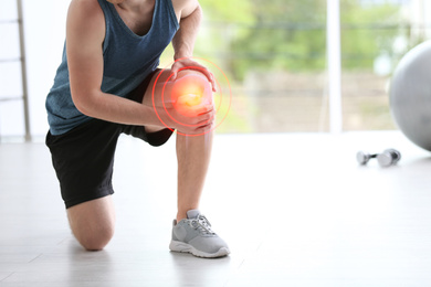 Image of Man in suffering from knee pain at gym, closeup