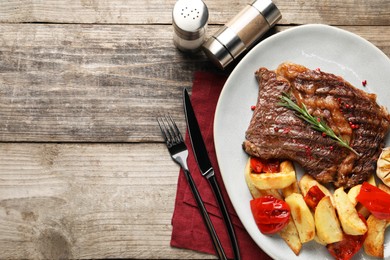 Photo of Delicious grilled beef steak and vegetables served on wooden table, top view. Space for text