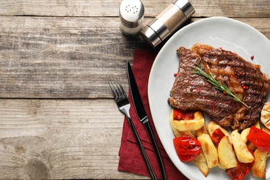 Delicious grilled beef steak and vegetables served on wooden table, top view. Space for text