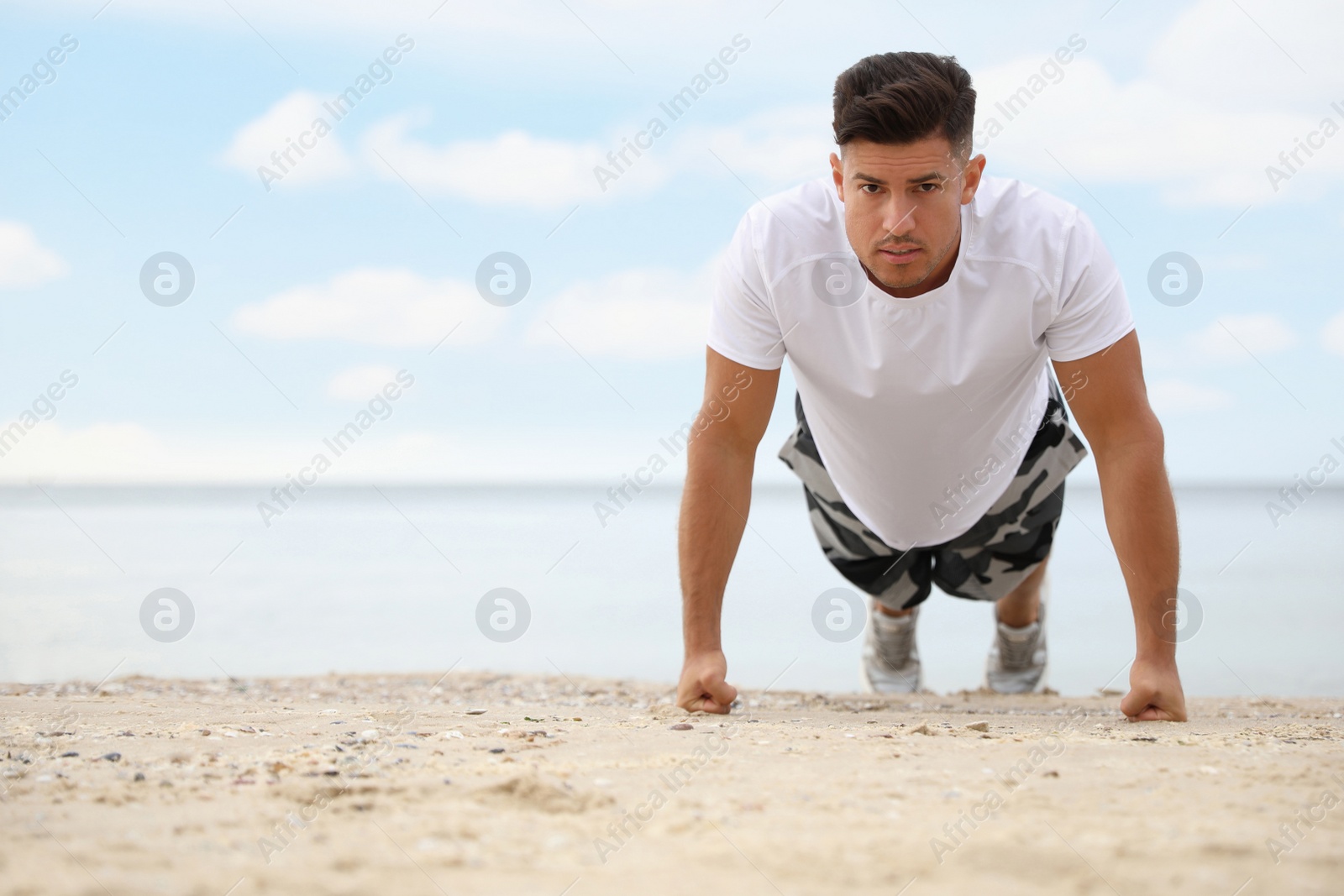Photo of Muscular man doing push up on beach, space for text. Body training