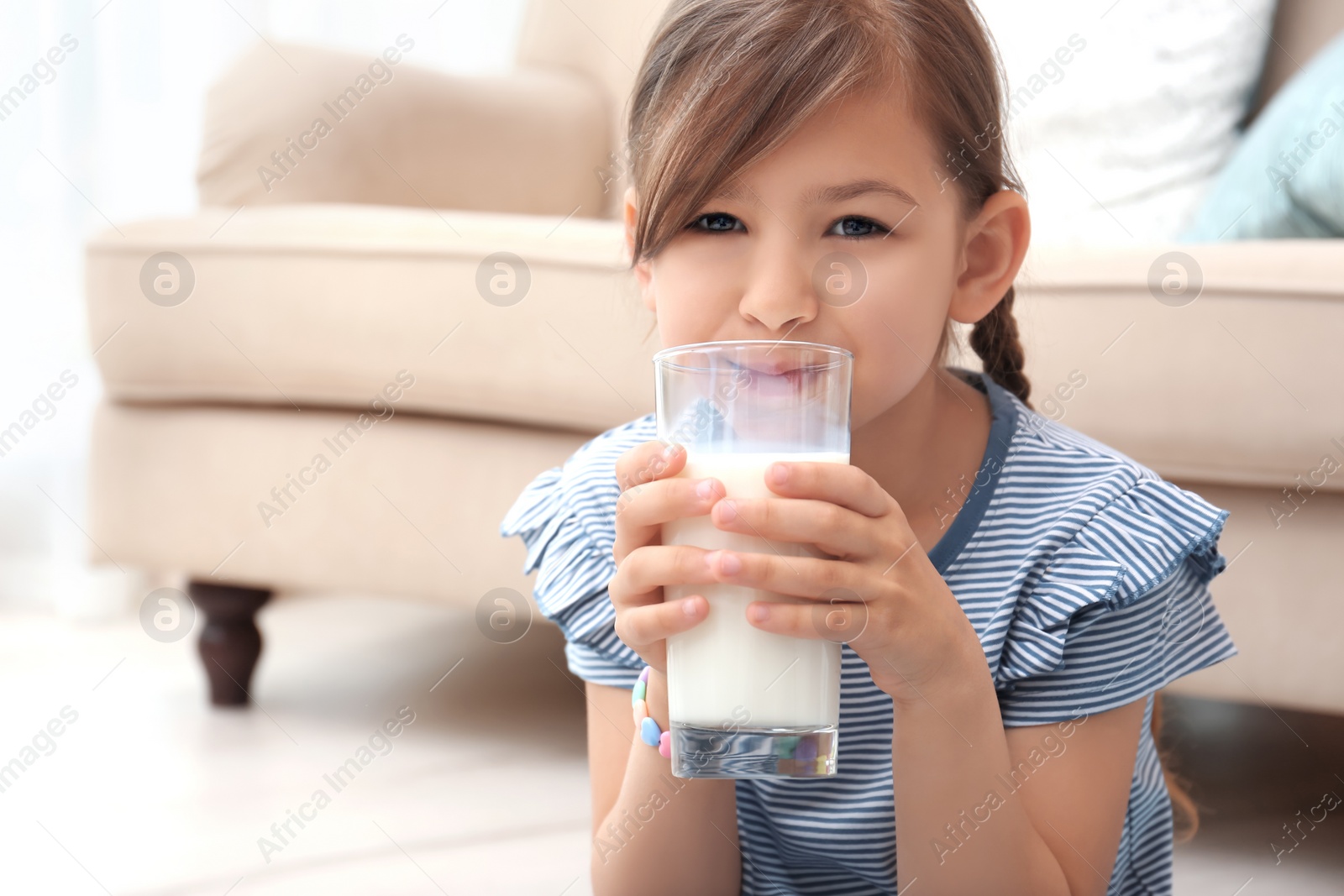 Photo of Cute little girl drinking milk at home