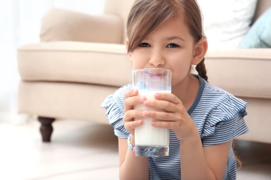 Photo of Cute little girl drinking milk at home