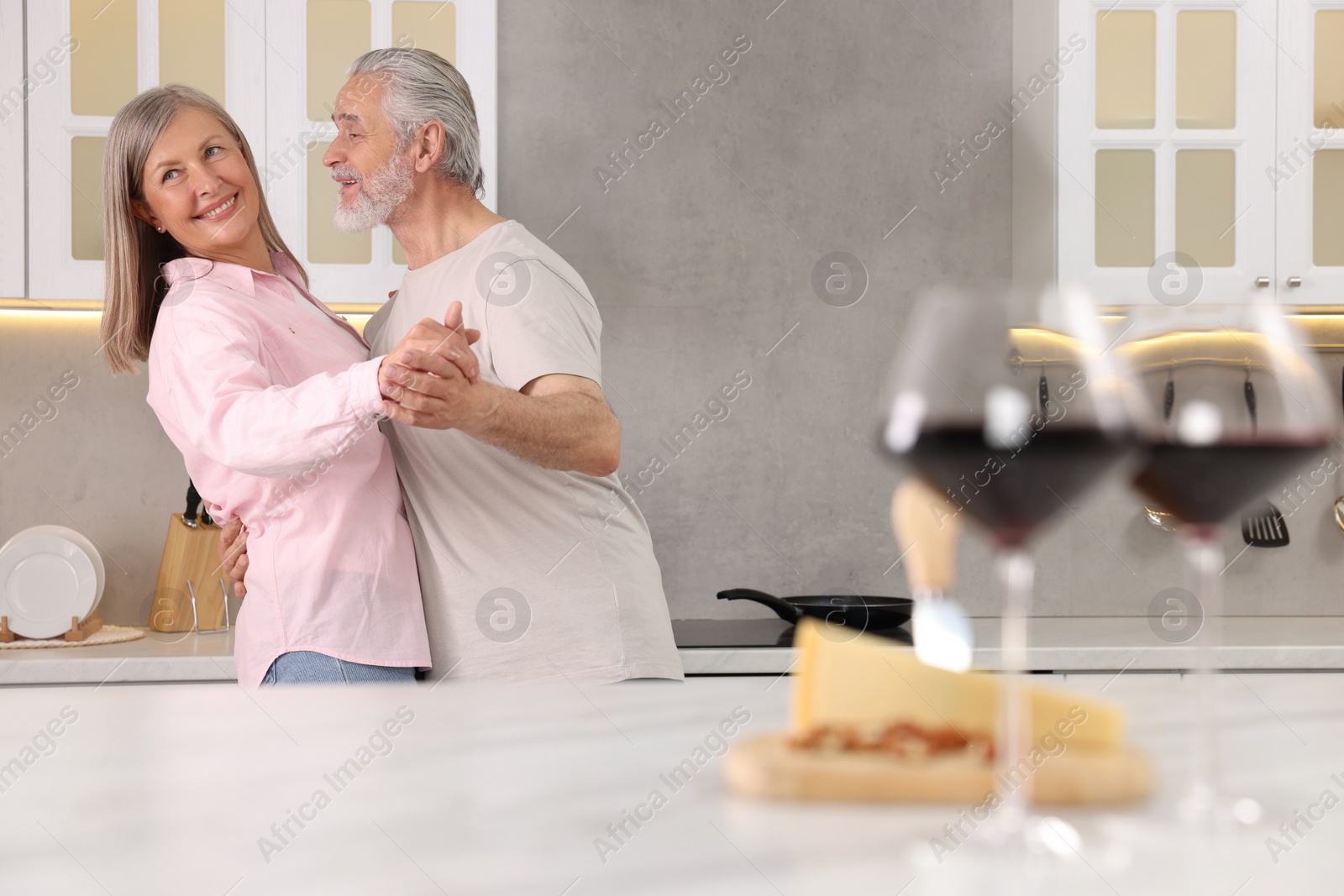 Photo of Happy affectionate senior couple dancing in kitchen, space for text
