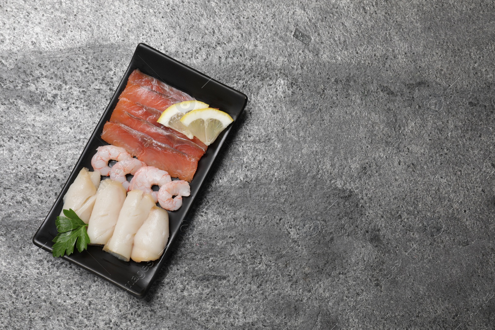Photo of Sashimi set served with lemon and parsley on light grey table, top view. Space for text