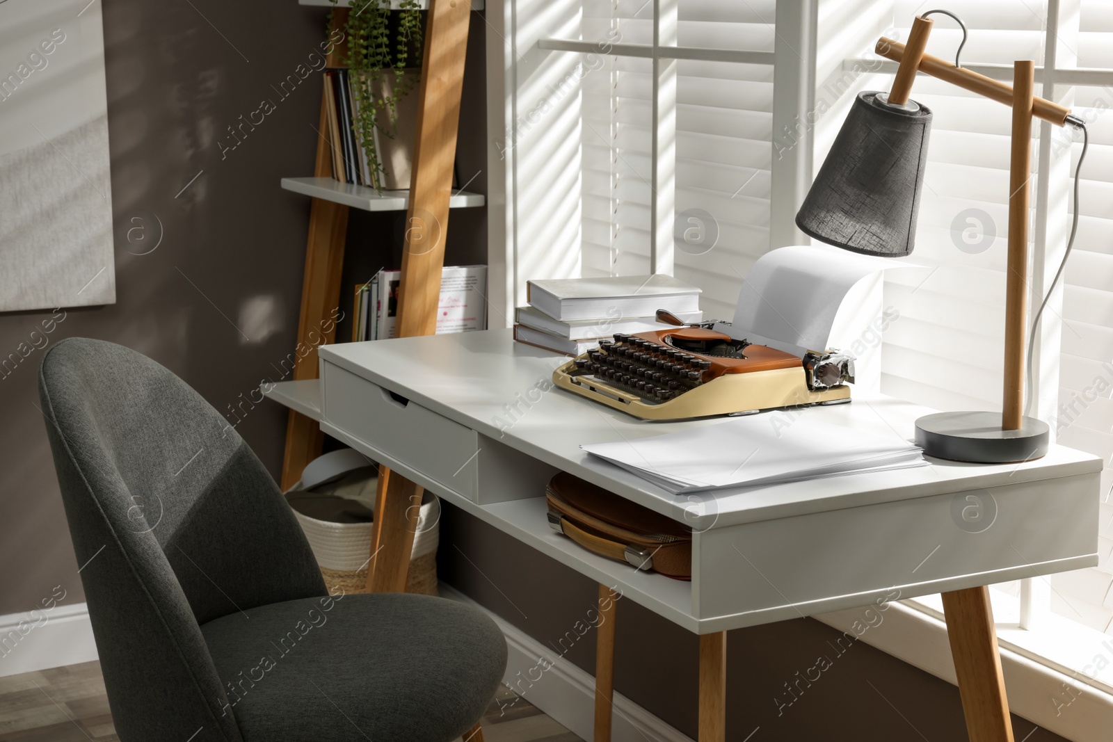 Photo of Comfortable writer's workplace interior with typewriter on desk in front of window