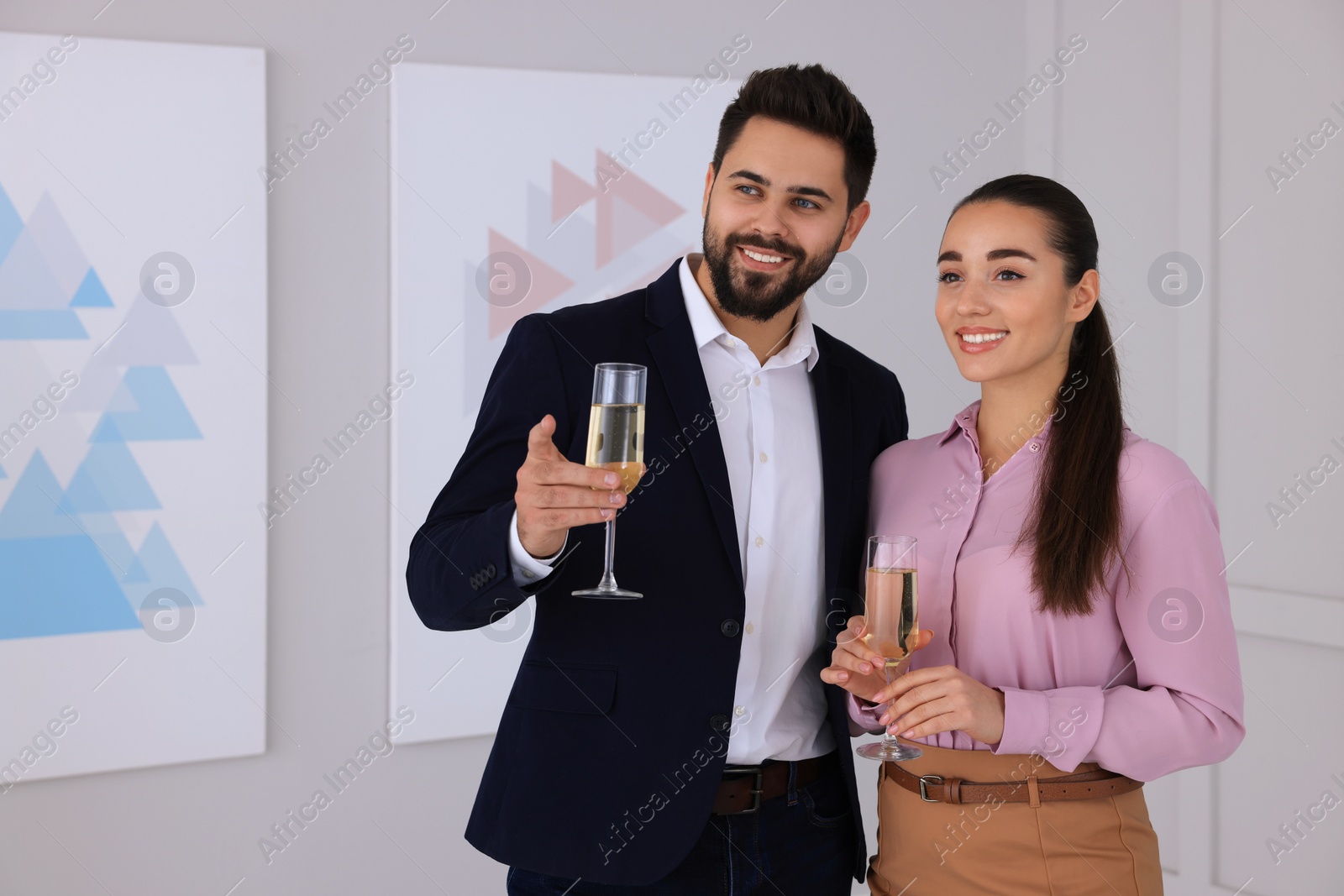 Photo of Young couple with glasses of champagne at exhibition in art gallery