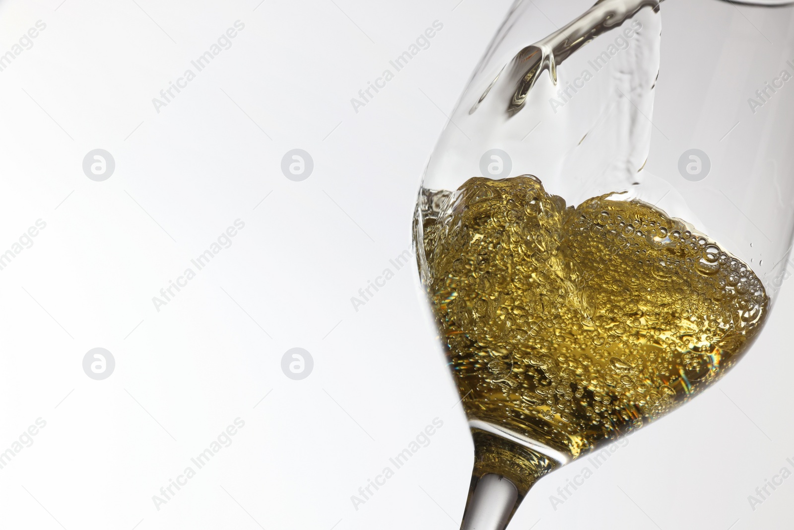 Photo of Pouring tasty aromatic wine in glass on white background, closeup. Space for text