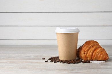 Photo of Coffee to go. Paper cup with tasty drink, croissant and beans on white wooden table. Space for text
