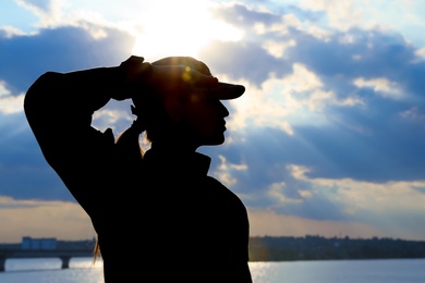 Photo of Female soldier in uniform saluting outdoors. Military service