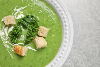 Tasty kale soup with croutons on grey table, top view