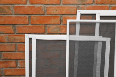 Set of window screens near brick wall. Space for text