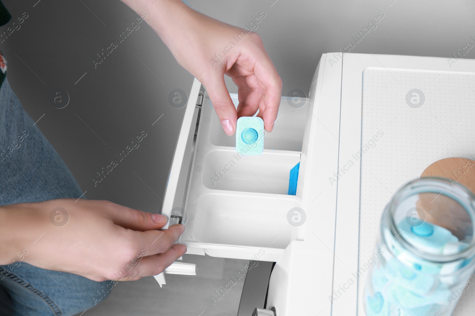 Photo of Woman putting water softener tablet into washing machine, closeup