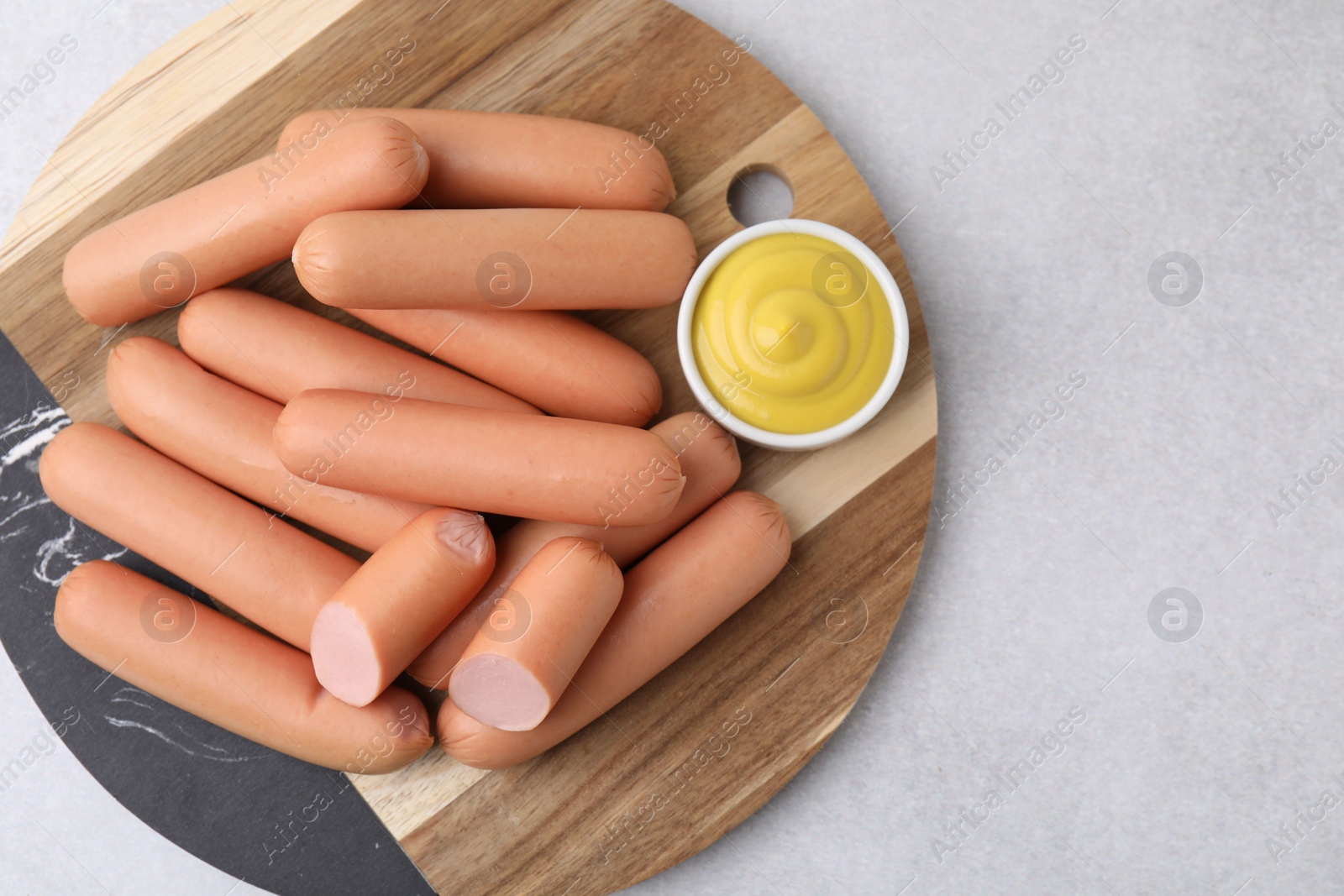 Photo of Delicious boiled sausages and sauce on light gray table, top view. Space for text