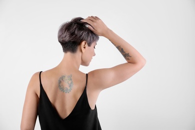 Trendy young woman with tattoos on white background. Space for text