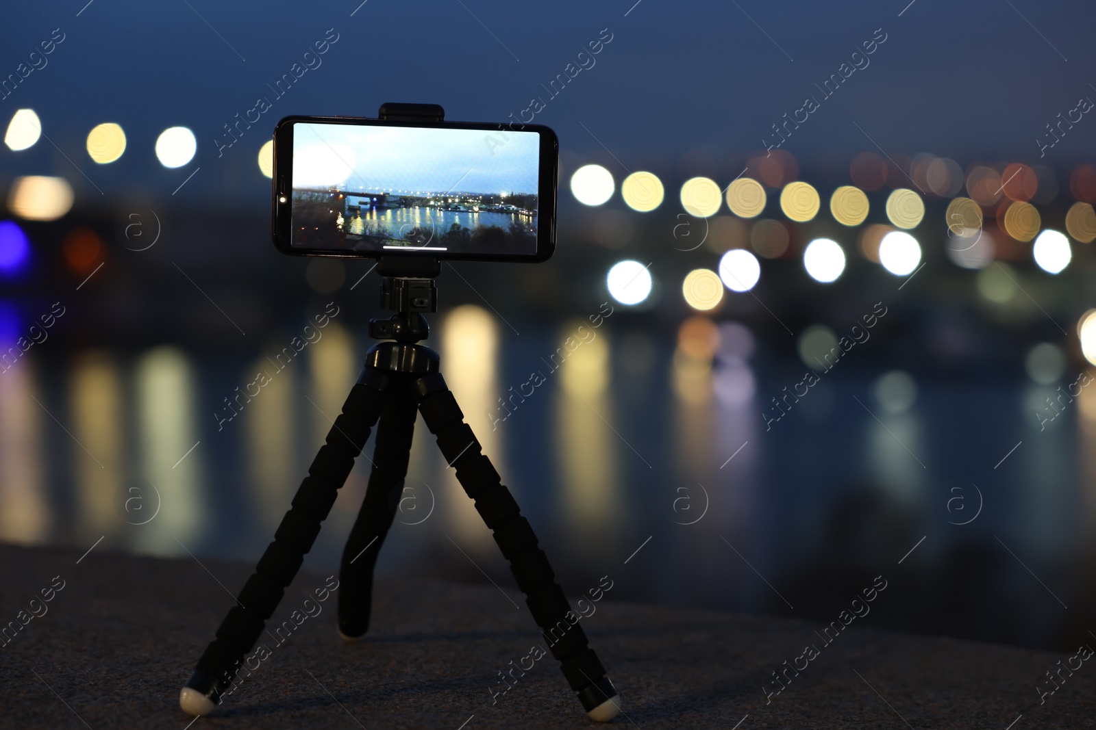 Photo of Taking photo with smartphone on tripod near river at night