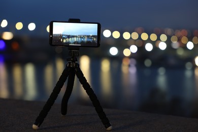 Photo of Taking photo with smartphone on tripod near river at night