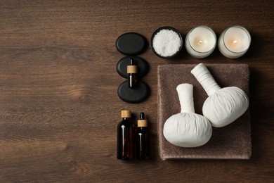 Photo of Flat lay composition with herbal massage bags and other spa products on wooden table, space for text