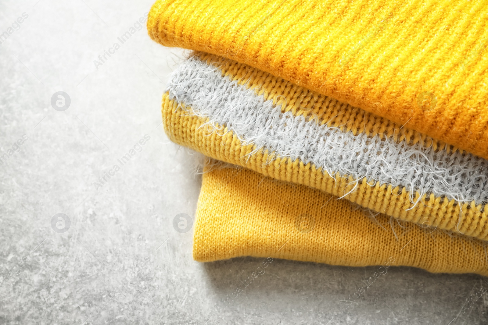 Photo of Stack of warm knitted clothes on light background