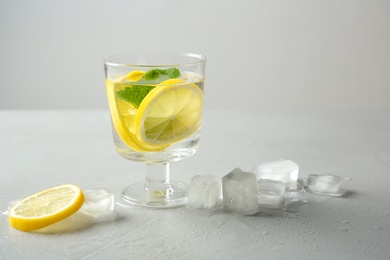 Photo of Glass with lemon water and ice cubes on table