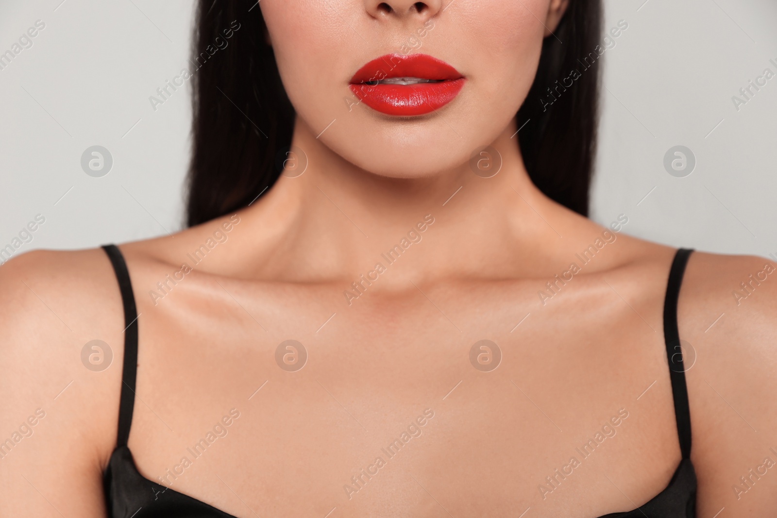 Photo of Young woman wearing beautiful red lipstick on light gray background, closeup