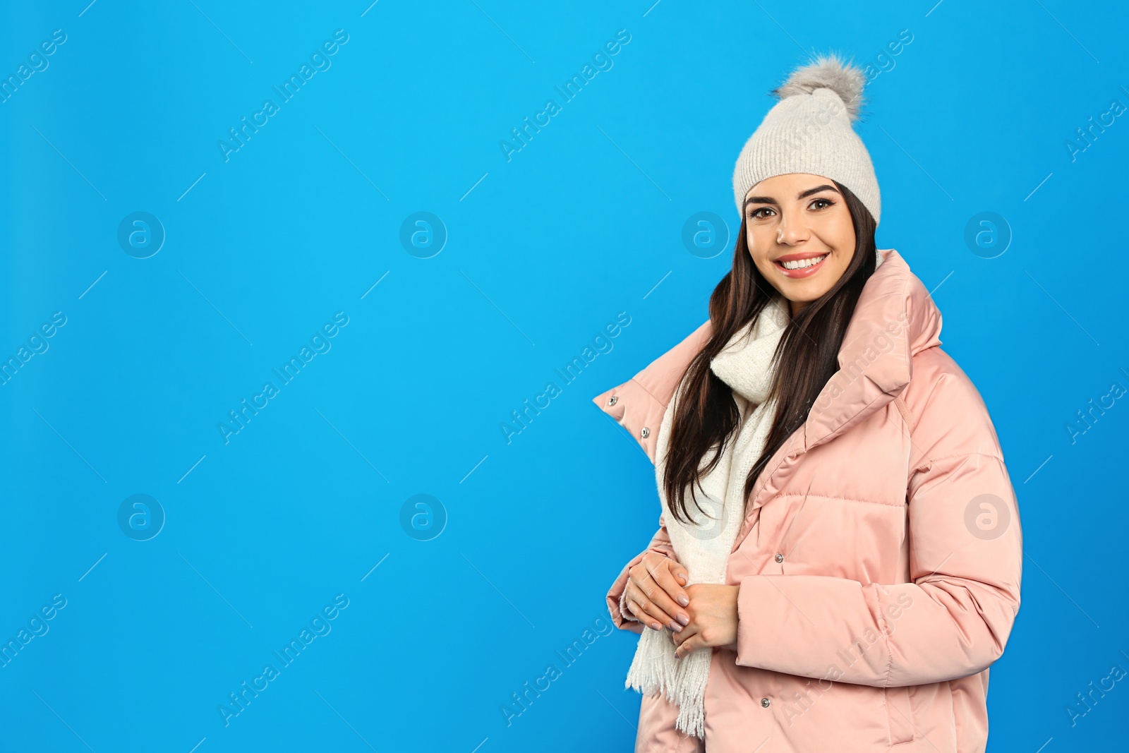 Photo of Happy young woman in warm clothes on blue background, space for text. Winter vacation