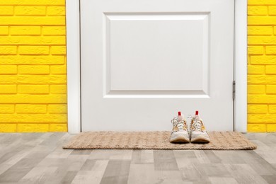Photo of Shoes on door mat in hallway, space for text
