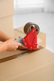 Woman packing carton box indoors, closeup. Moving day
