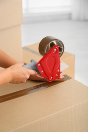 Photo of Woman packing carton box indoors, closeup. Moving day