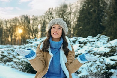 Portrait of smiling woman playing with snow in winter park