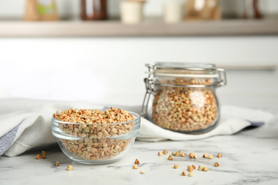 Uncooked green buckwheat grains on white marble table