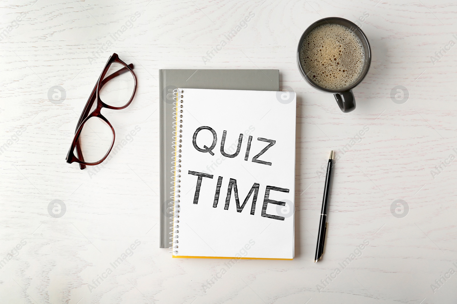 Image of Phrase Quiz Time written in notebook, cup of coffee, glasses and pen on white wooden table, flat lay