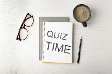 Phrase Quiz Time written in notebook, cup of coffee, glasses and pen on white wooden table, flat lay