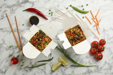 Photo of Boxes of wok noodles with vegetables and meat on white marble table, flat lay