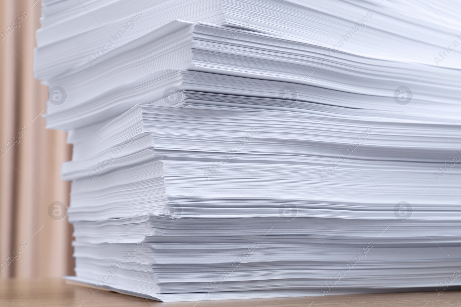 Photo of Stack of paper sheets on wooden table indoors, closeup