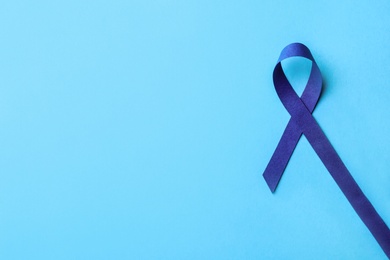 Photo of Blue awareness ribbon on color background, top view with space for text. Symbol of social and medical issues