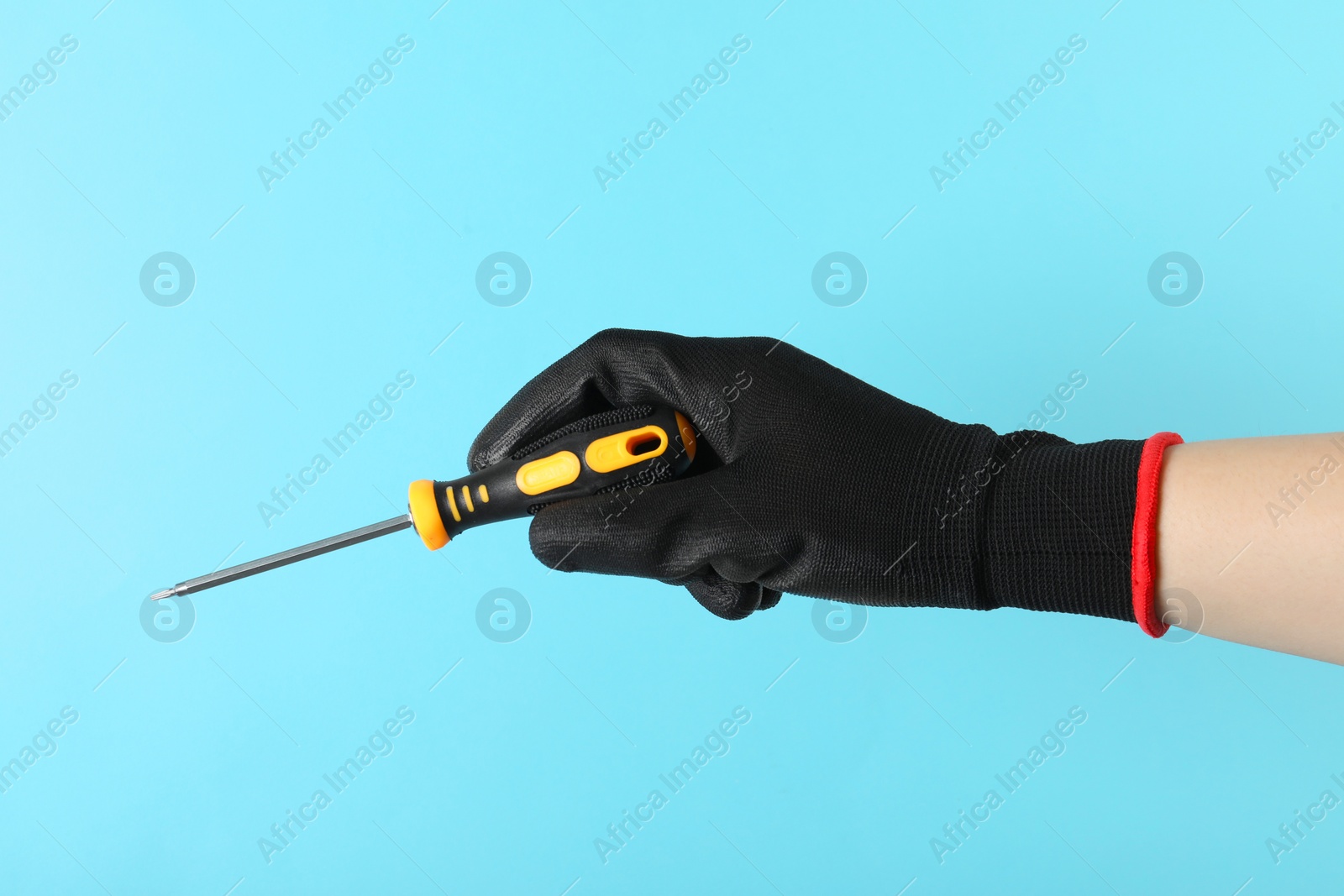 Photo of Woman holding screwdriver on light blue background, closeup