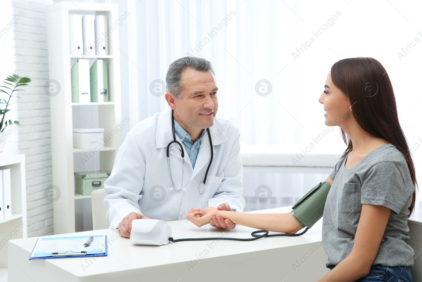 Photo of Young woman visiting doctor in hospital. Measuring blood pressure and checking pulse