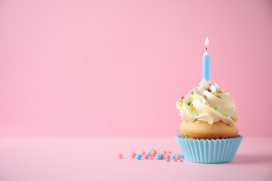 Photo of Delicious birthday cupcake with candle on pink background. Space for text