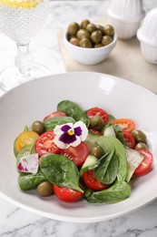 Photo of Delicious salad with vegetables and olives on white marble table, closeup