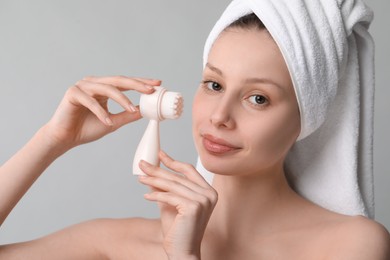 Photo of Washing face. Young woman with cleansing brush on grey background