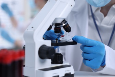 Photo of Scientist working with microscope in laboratory, closeup