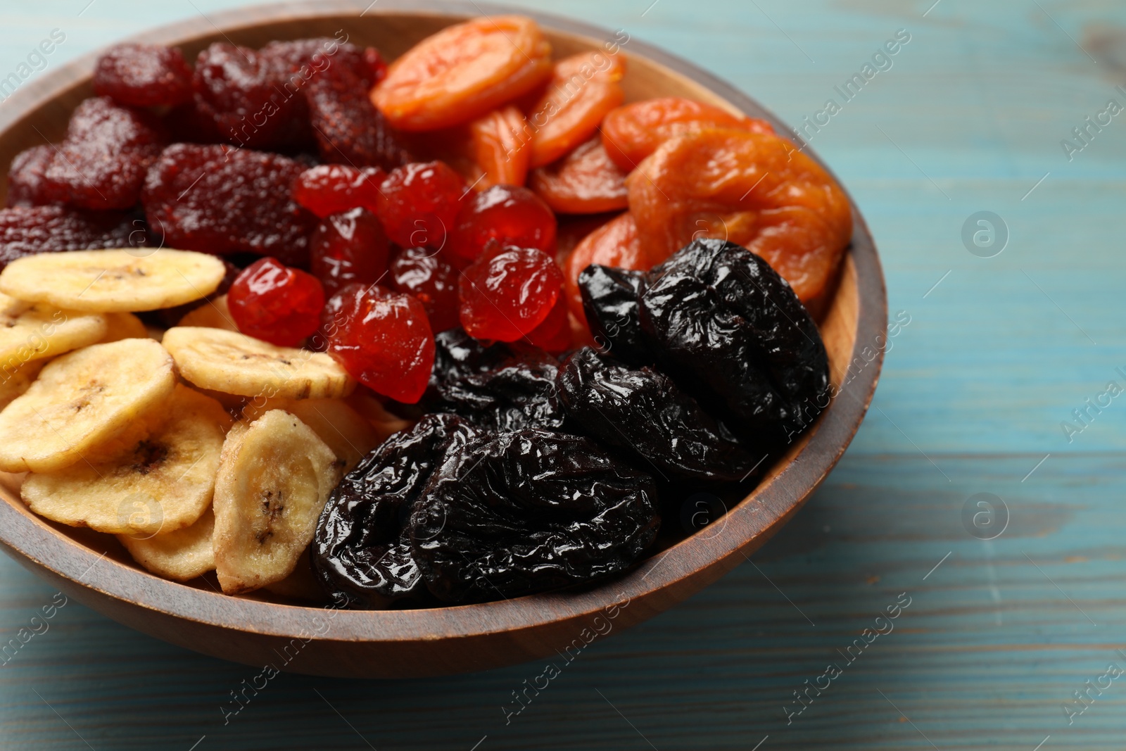 Photo of Mix of delicious dried fruits on light blue wooden table, closeup