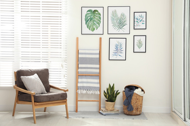 Photo of Beautiful paintings of tropical leaves on white wall in room interior