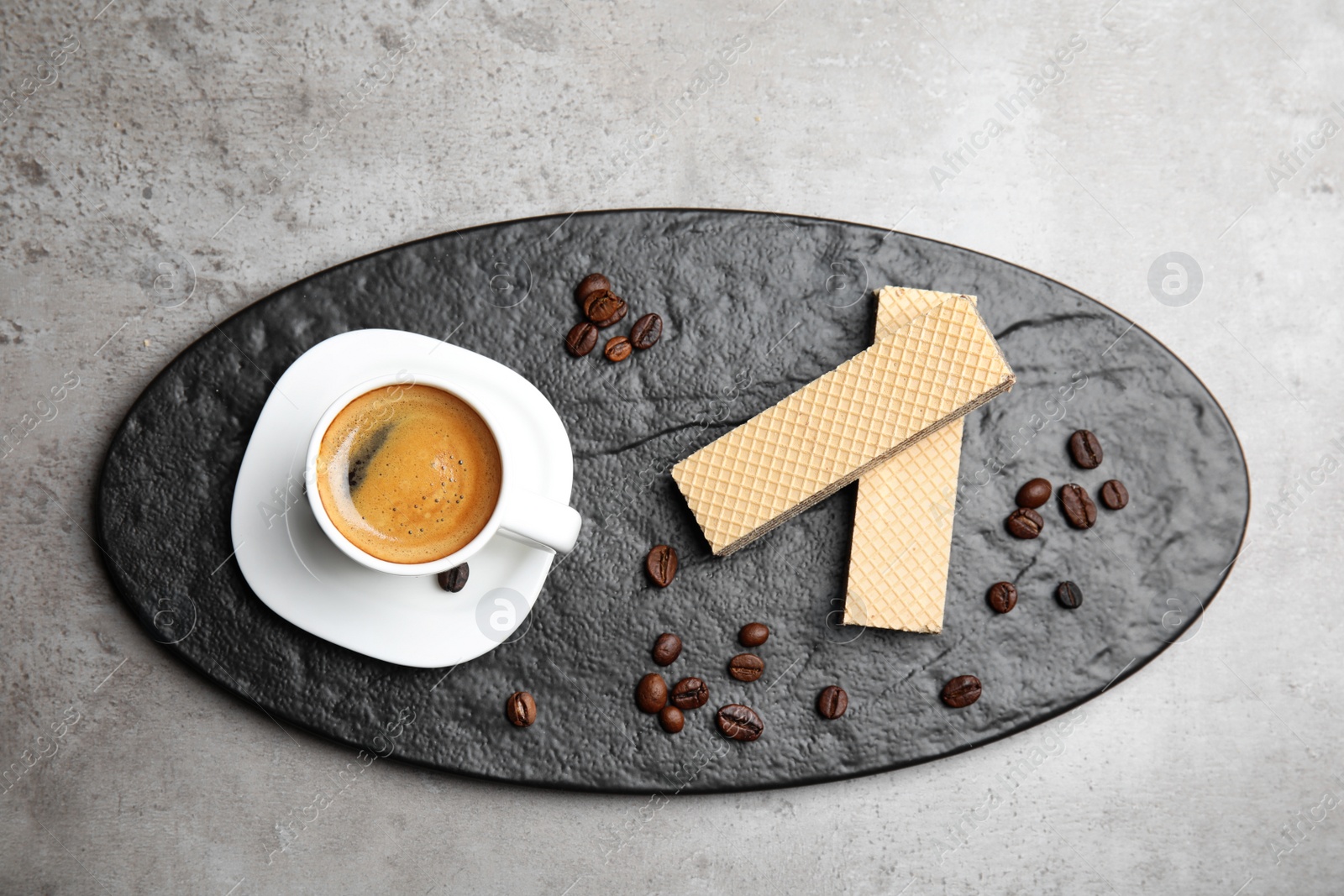 Photo of Delicious wafers and cup of coffee for breakfast on grey table, flat lay
