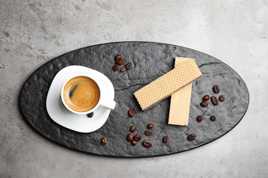 Delicious wafers and cup of coffee for breakfast on grey table, flat lay