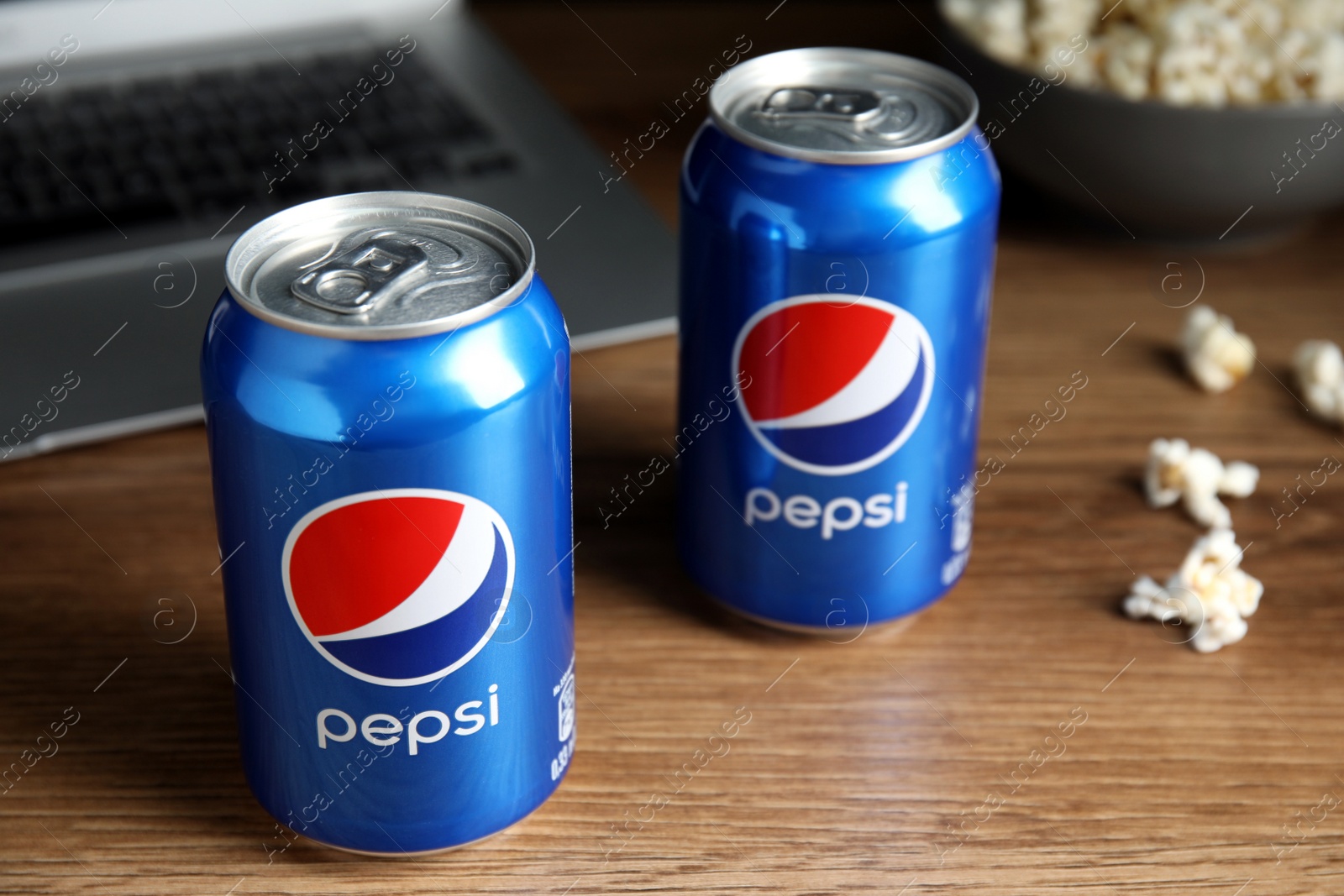 Photo of MYKOLAIV, UKRAINE - FEBRUARY 17, 2021: Cans of Pepsi and pop corn on wooden table